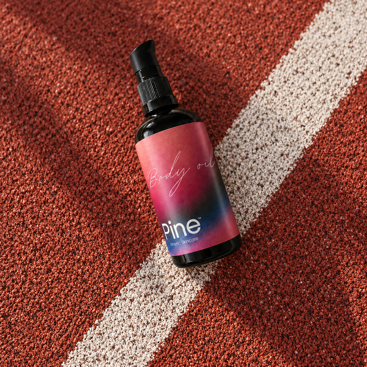 Pine Body Oil i flaske på en rød løbebane