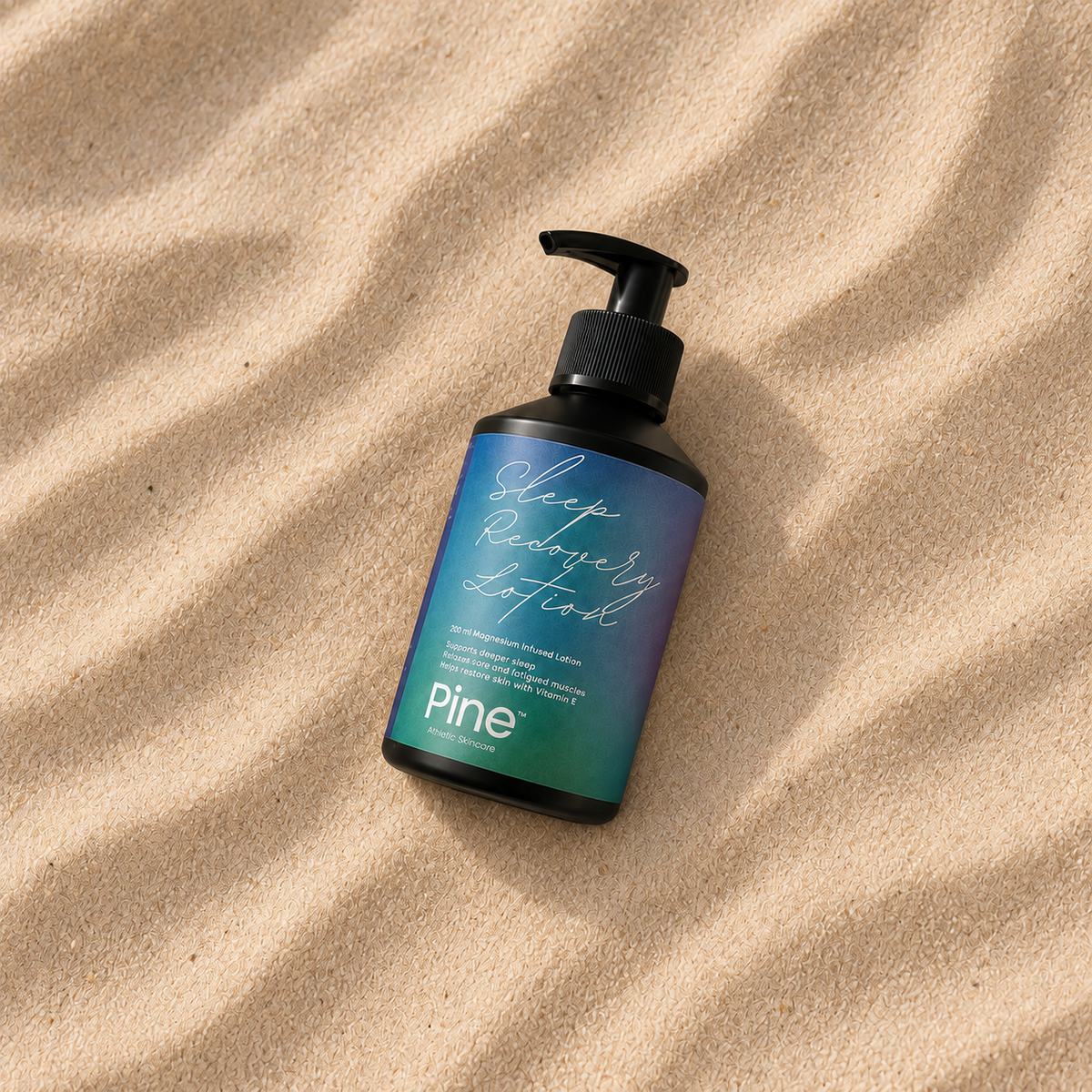 Pine Sleep Recovery Lotion i flaske på bølget sand